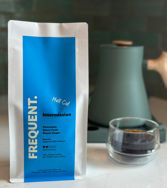 Coffee bag with Intermission half caf coffee from Frequent Coffee next to a coffee cup