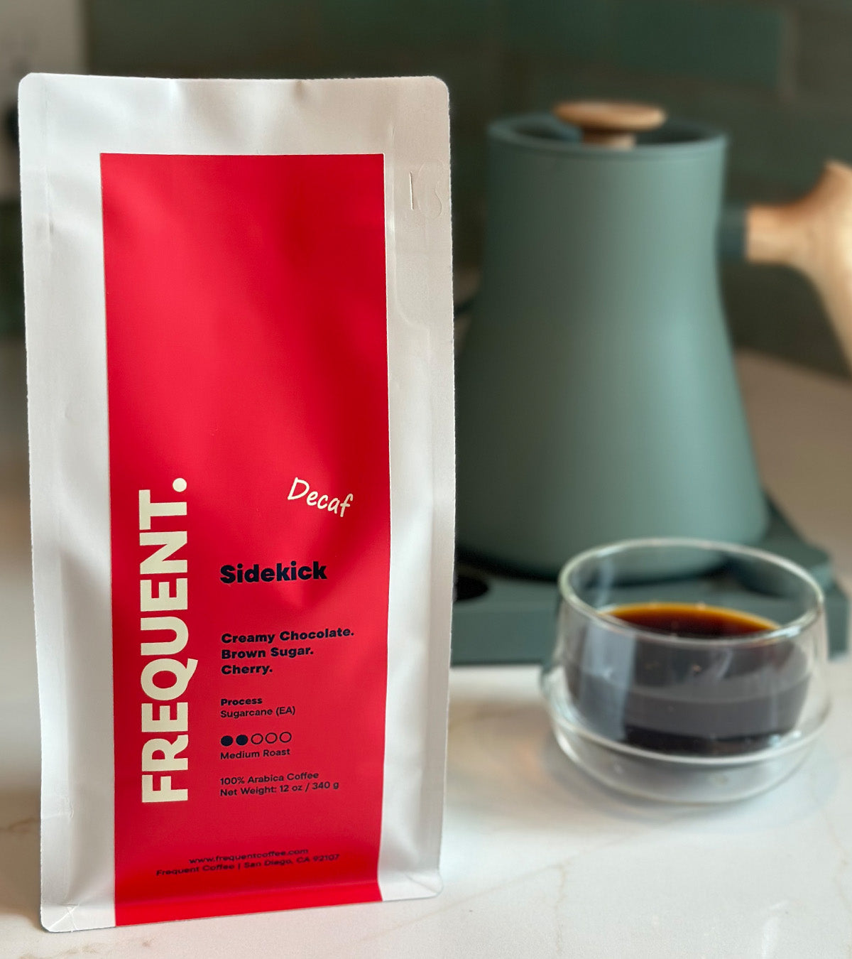 A bag of Sidekick decaf coffee from Frequent next to a coffee cup